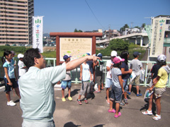 PR看板前で施設の説明を受けている写真